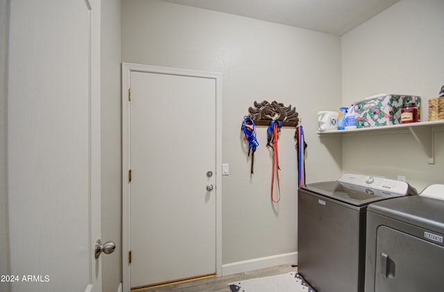 laundry room with washing machine and clothes dryer and light hardwood / wood-style flooring