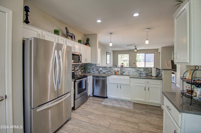 kitchen with appliances with stainless steel finishes, light hardwood / wood-style floors, kitchen peninsula, ceiling fan, and white cabinets