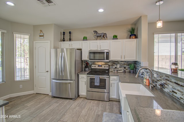 kitchen with a wealth of natural light, stainless steel appliances, and white cabinetry