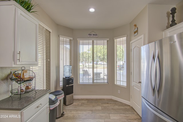 kitchen featuring light hardwood / wood-style flooring, dark stone countertops, stainless steel fridge, and white cabinetry