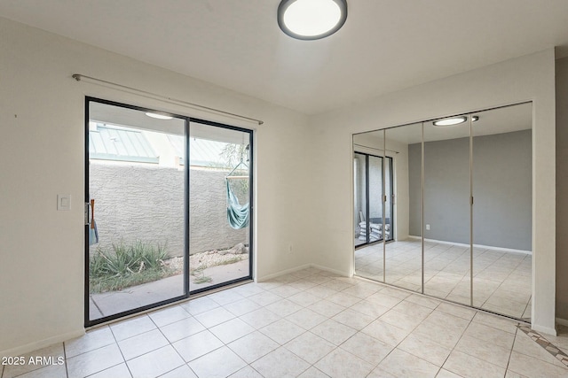 unfurnished bedroom featuring light tile patterned flooring, access to outside, and a closet