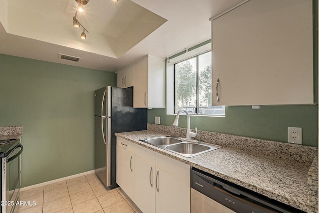 kitchen featuring white cabinets, a raised ceiling, sink, light tile patterned floors, and stainless steel appliances