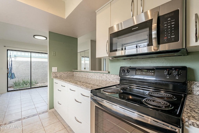 kitchen featuring light tile patterned flooring, light stone countertops, white cabinetry, and black / electric stove