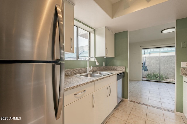 kitchen with white cabinets, stainless steel appliances, light tile patterned flooring, and sink