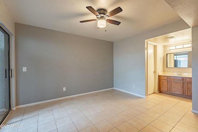 unfurnished bedroom featuring light tile patterned floors, connected bathroom, ceiling fan, and sink