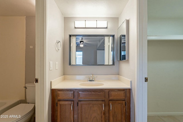 bathroom with ceiling fan, a washtub, a textured ceiling, toilet, and vanity