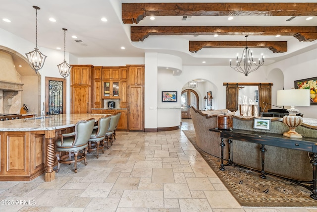 kitchen featuring a chandelier, a kitchen breakfast bar, hanging light fixtures, light stone counters, and a spacious island