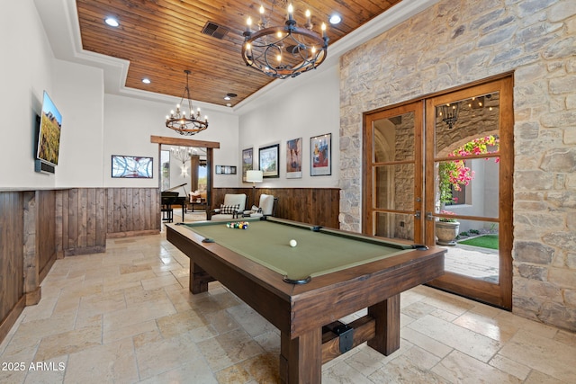 playroom with wood walls, ornamental molding, wooden ceiling, an inviting chandelier, and french doors