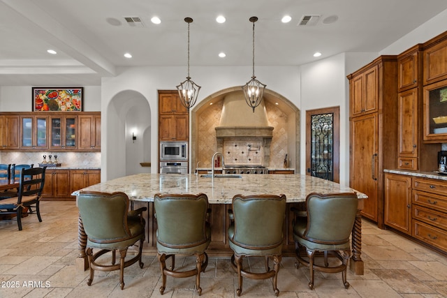 kitchen with stainless steel appliances, a large island, decorative light fixtures, and a kitchen bar