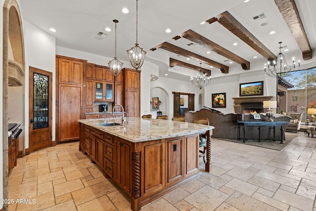 kitchen with hanging light fixtures, light stone countertops, sink, and a spacious island