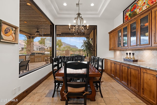 dining room featuring a mountain view, ceiling fan with notable chandelier, and a tray ceiling