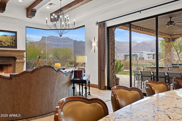 tiled dining room featuring a mountain view, ceiling fan with notable chandelier, and beamed ceiling