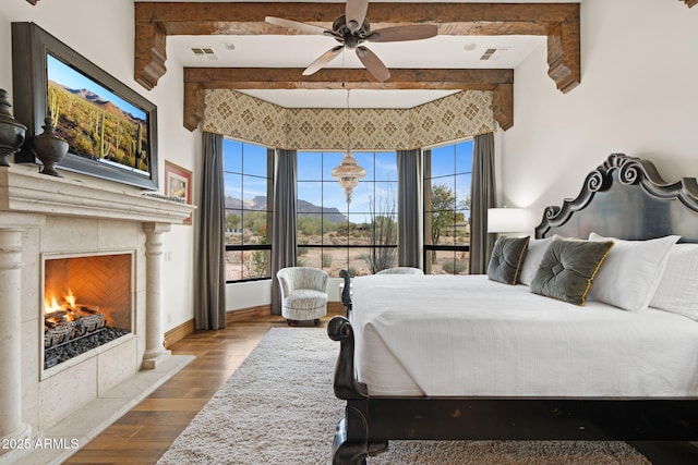 bedroom with multiple windows, hardwood / wood-style floors, beam ceiling, and a fireplace