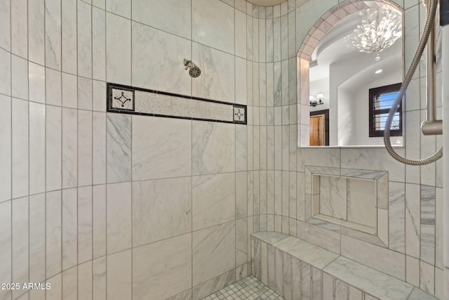 bathroom featuring tiled shower and an inviting chandelier