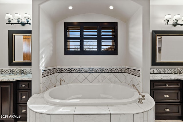 bathroom with vanity, tiled tub, and decorative backsplash