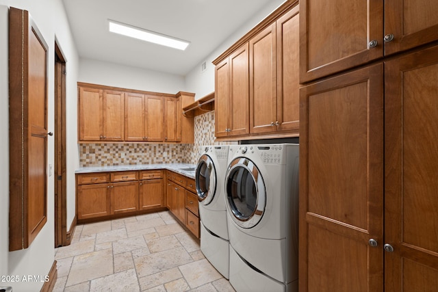 clothes washing area with cabinets and washing machine and dryer