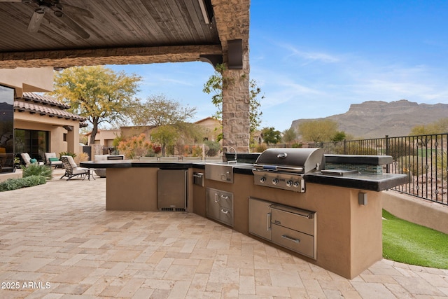 view of patio with area for grilling, a mountain view, grilling area, and ceiling fan