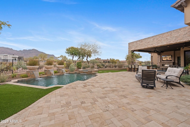 view of pool with an outdoor stone fireplace, a patio, a mountain view, pool water feature, and an in ground hot tub