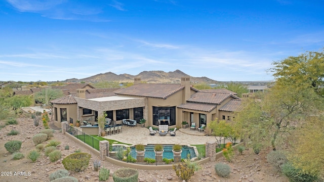 rear view of property with a mountain view, a patio area, an outdoor bar, and an outdoor fire pit