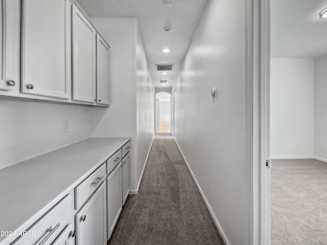 corridor featuring dark colored carpet