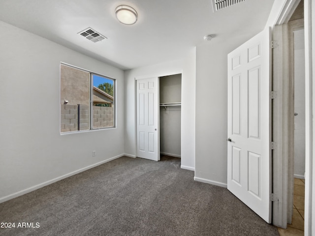 unfurnished bedroom with dark carpet and a closet