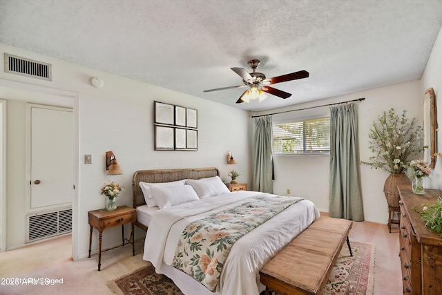 bedroom featuring a textured ceiling, visible vents, and ceiling fan