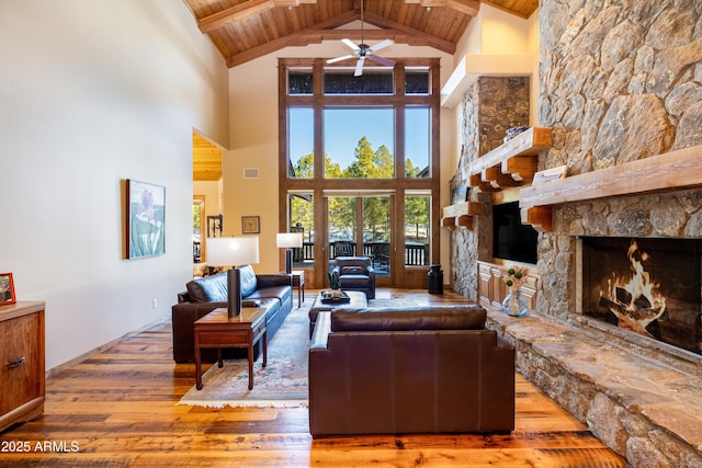 living area featuring wood ceiling, beam ceiling, a fireplace, a ceiling fan, and wood-type flooring