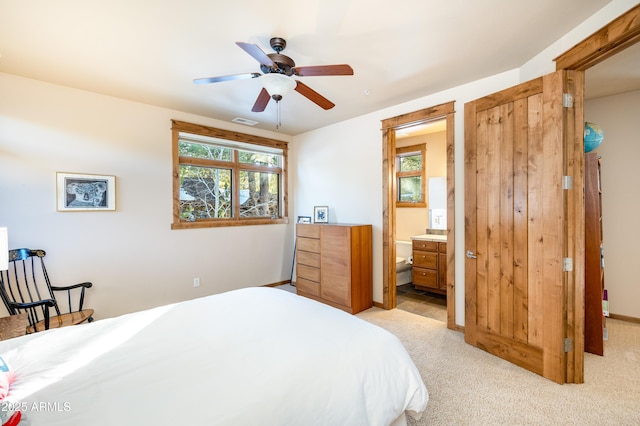 bedroom featuring visible vents, connected bathroom, baseboards, ceiling fan, and light carpet