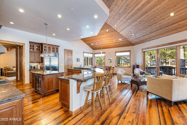 kitchen featuring stainless steel built in fridge, open floor plan, a large island with sink, and brown cabinetry