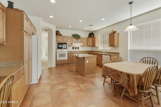 kitchen with white appliances, decorative light fixtures, a kitchen island, light tile patterned flooring, and sink