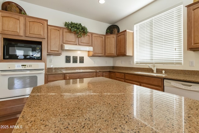 kitchen featuring sink, white appliances, and light stone counters