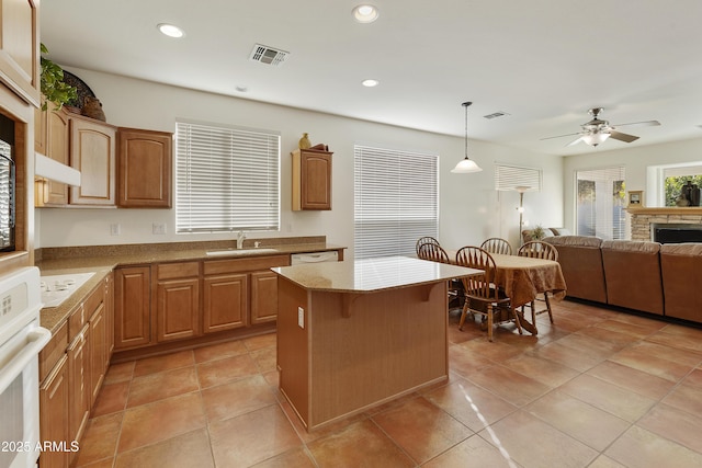 kitchen featuring white appliances, pendant lighting, a kitchen island, ceiling fan, and sink