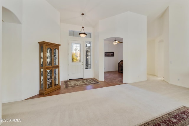 carpeted entrance foyer featuring ceiling fan and high vaulted ceiling