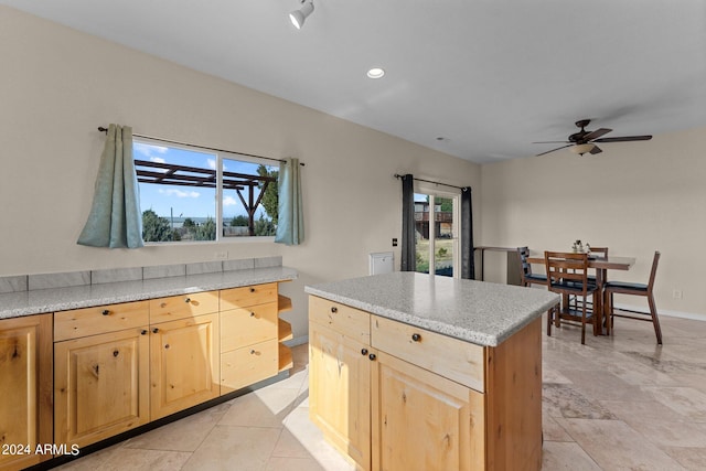 kitchen featuring light brown cabinetry, a center island, and ceiling fan