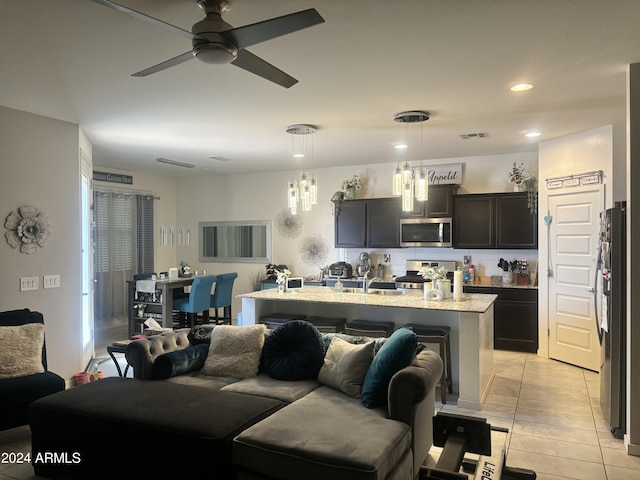 living room featuring light tile patterned floors and ceiling fan with notable chandelier