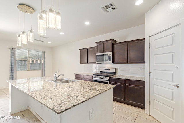 kitchen featuring a center island with sink, visible vents, appliances with stainless steel finishes, light stone countertops, and a sink