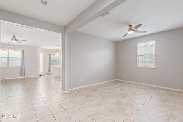 tiled empty room with ceiling fan with notable chandelier