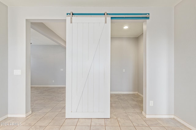 tiled spare room featuring a barn door