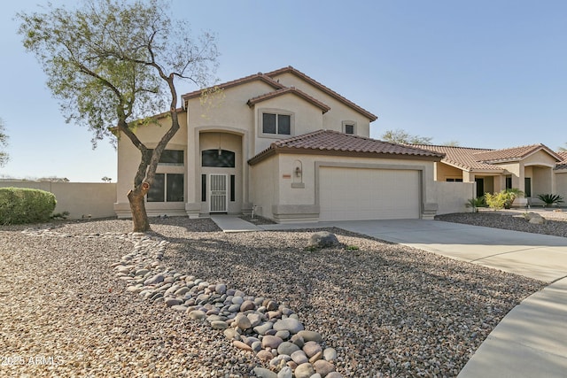 mediterranean / spanish-style home featuring stucco siding, concrete driveway, an attached garage, and fence