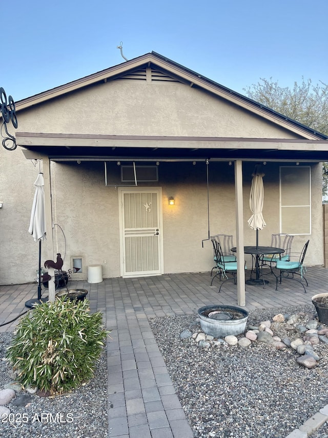 rear view of house featuring an outdoor fire pit, a patio area, and stucco siding