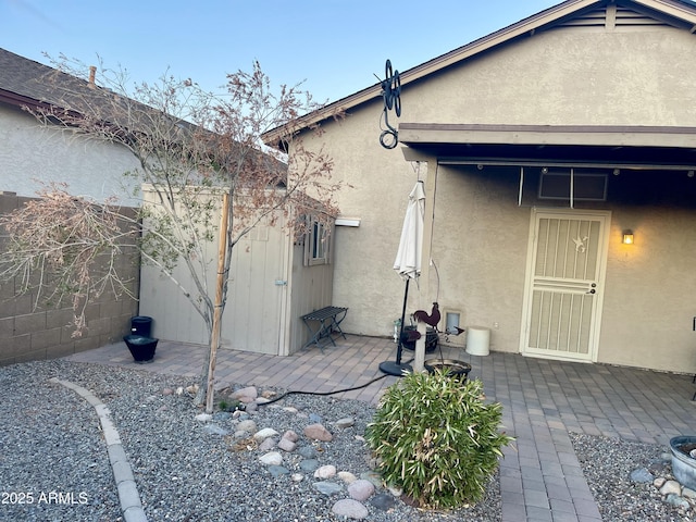 rear view of property with fence, an outdoor structure, a patio, and stucco siding