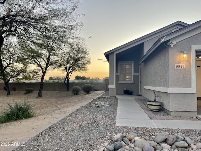 doorway to property with fence and stucco siding