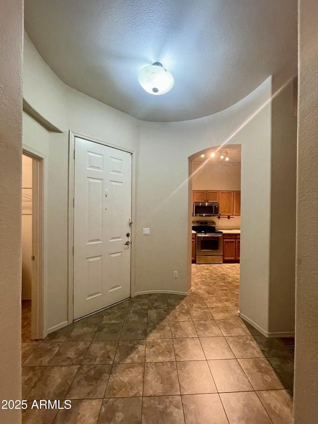 tiled entryway with a textured ceiling and baseboards