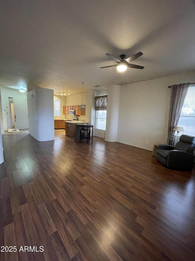 unfurnished living room featuring a ceiling fan and dark wood-style flooring