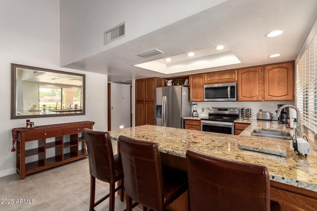 9243 W Kimberly Way, Peoria, AZ 85382 - kitchen featuring visible vents, light stone countertops, a sink, a peninsula, and stainless steel appliances