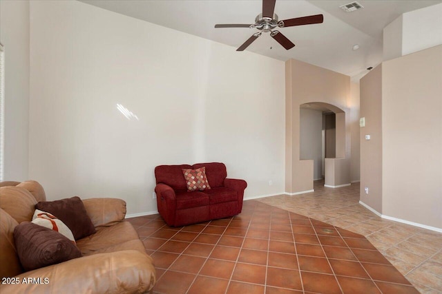 tiled living room with arched walkways, vaulted ceiling, visible vents, and baseboards