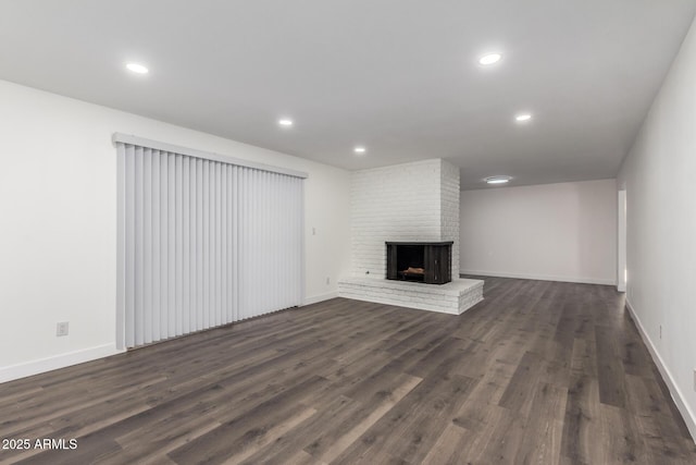 unfurnished living room with a brick fireplace and dark wood-type flooring