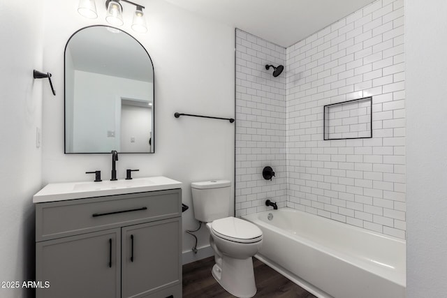 full bathroom featuring wood-type flooring, toilet, tiled shower / bath combo, and vanity