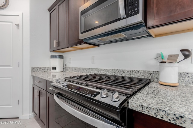 kitchen with light stone counters, dark brown cabinetry, appliances with stainless steel finishes, and light tile patterned flooring