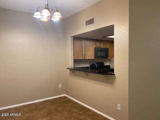 kitchen featuring a kitchen bar, dark countertops, visible vents, black microwave, and baseboards